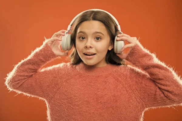 Aplikacja radiowa dla urządzenia mobilnego. Muzyka to jej dusza. Dziewczyna cute little dziecko nosić słuchawki słuchać muzyki. Dziecko słuchać muzyki pomarańczowe tło. Zalecana muzyka w oparciu o początkowe zainteresowanie — Zdjęcie stockowe