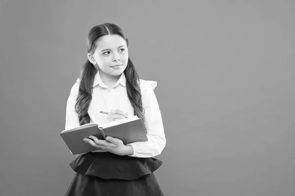 Lezione di lettura. Bambino felice godere di studio e lettura del libro. Torniamo a scuola. ottenere informazioni libro modulo. piccola ragazza a scuola lezione. scolaretta che scrive appunti su sfondo arancione. copiare spazio. lezione . — Foto Stock