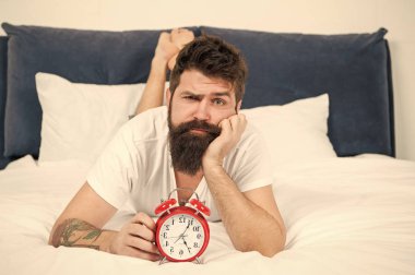 Bitkin hissediyorum. çalar saat ile yorgun sakallı adam hipster. yatak odasında acımasız uykulu adam. zaman yönetimi. yatakta pijama sakallı olgun erkek. uykuda ve uyanık. enerji ve yorgunluk