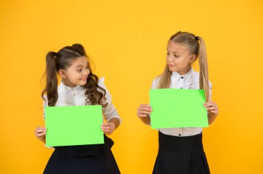 Bilgi sağlamak. Küçük çocuklar sarı arka plan hakkında bilgi için boş yeşil kağıtlar tutan. Küçük kızlar bilgi bildirimini sergiliyorlar. Gelecek akıllı reklam, kopyalama alanı