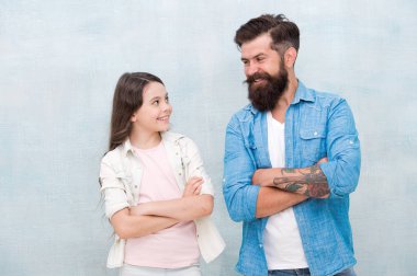 Mutlu ol ve gülümse. Mutlu bir aile. Mutlu baba ve küçük kızı kollarını gri arka planda çapraz tutmak. Sakallı adam ve küçük çocuk mutlu gülümseyerek.
