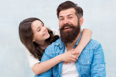 Çocuk sevilive önemsenmiş hissediyor. Mutlu küçük çocuk kızı ve baba sevinçle gülümsüyor. Küçük kız çocuk gri arka plan üzerinde baba sarılma. Mutlu bir çocuk yetiştirmek