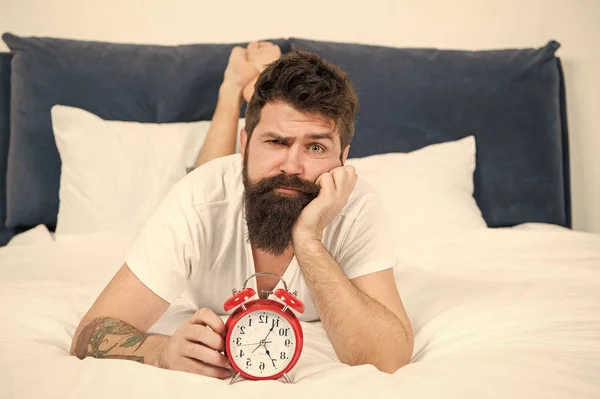 Sinto-me exausta. homem barbudo cansado hipster com despertador. Homem sonolento brutal no quarto. gestão do tempo. macho maduro com barba no pijama na cama. dormindo e acordado. energia e cansaço — Fotografia de Stock