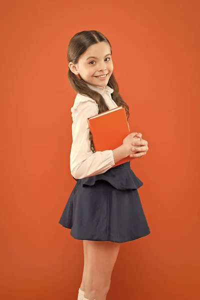 子供の頃の思い出オレンジ色の背景にメモを書く女子高生。ノートを作るための日記。情報フォームブックを取得します。学校に戻る文学のレッスンを受けた女子高生。制服を着た小さな女の子 — ストック写真