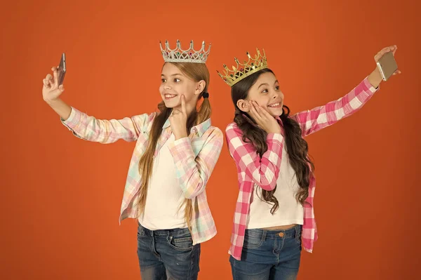 Эгоцентричная принцесса. Дети носят золотые короны символы принцессы. Предупреждающие признаки избалованного ребенка. Избегайте воспитания избалованных детей. Девушки фотографируют смартфоны с селфи. Избалованные дети — стоковое фото