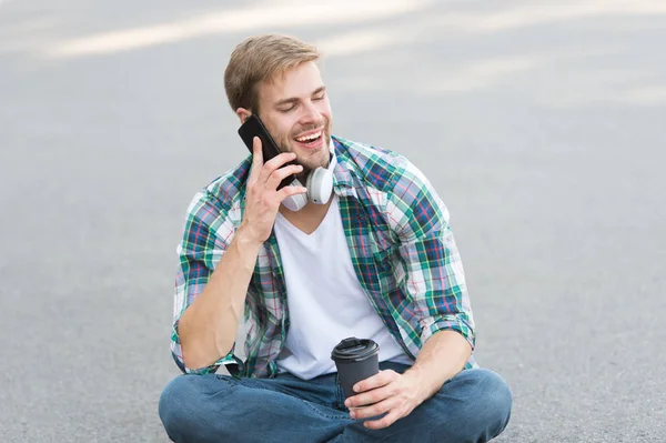 Llama a un amigo. Guy estudiante despreocupado disfrutar del café al aire libre. Balance de vida. Bienestar y salud. Tomando un café. El hombre se sienta en el suelo mientras bebe café. Relájate y recarga. Diviértete durante el descanso — Foto de Stock