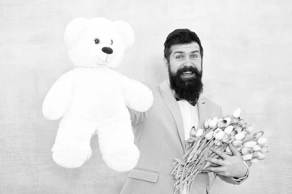 Γυναικεία μέρα. Επίσημος επιχειρηματίας με παιχνίδι αρκούδων. Ανοιξιάτικο μπουκέτο. 8 Μαρτίου. νύφη γαμπρός στο γαμήλιο πάρτι. μουσάτος άντρας με παπιγιόν με λουλούδια τουλίπας. ερωτικό ραντεβού με λουλούδια. Να τα εκατοστήσεις — Φωτογραφία Αρχείου