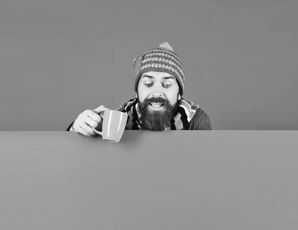 Mann mit warmem Hut hält braune Tasse auf grünem Hintergrund — Stockfoto