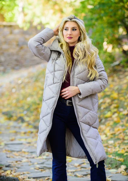 Puffer fashion trend concept. Girl fashionable blonde walk in autumn park. Woman wear warm grey jacket. Jacket everyone should have. Oversized jacket trend. How to rock puffer jacket like star