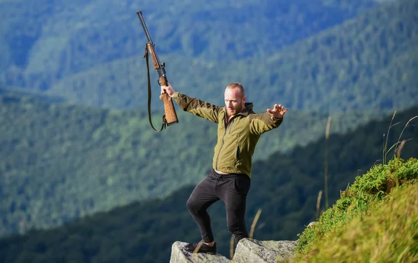 Walking in mountains. Hunting masculine hobby concept. Regulation of hunting. Hunter hold rifle. Nice day for hunt. Hunter spend leisure hunting. Man brutal gamekeeper nature landscape background