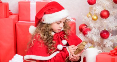 Noel Baba'ya mektup gönder. İstek listesi. Çocuk santa kostüm noel arifesinde tadını çıkarın. Çocuk Noel Baba'ya mektup yaz. Sevgili Noel Baba. Kız noel ağacı ve hediye kutusu yakınında kalem ve kağıt tutun. Mucizeye inan