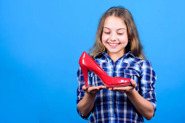 Awesome red stiletto shoes. Little fashionista kid with high heels. Female attribute. Shoes shop. Child play with moms shoes. Every girl dreaming about fashionable high heels. Glamour high heels