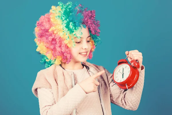 Zijn rusttijd. Gelukkig klein meisje met kleurrijke pruik haar wijzend op wekker voor de exacte tijd. Tijd concept. Het beoefenen van good time management — Stockfoto