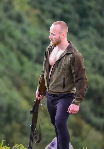 Caça ilegal. Homem caçador brutal com arma paisagem natural fundo. Conceito de caça furtiva. Poacher stand on edge of cliff. Hunter caçador furtivo à procura de vítima. Hunter com rifle ambiente natureza — Fotografia de Stock