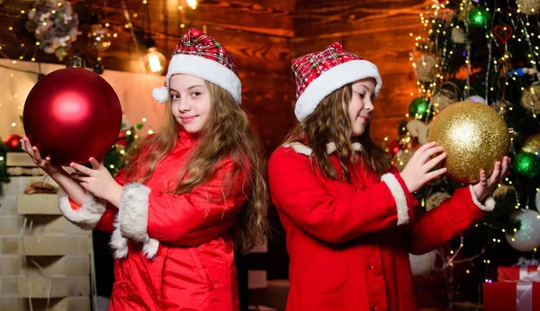 La familia celebra la Navidad. Concepto de unidad. Ambiente festivo el día de Navidad. Decora el árbol de Navidad juntos. Chicas hermanas Santa Claus disfraces. Niños lovely friends meet Christmas holiday — Foto de Stock