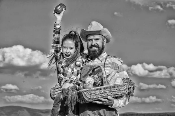 Man bearded rustic farmer with kid. Farmer family homegrown harvest. Only organic and fresh harvest. Father and daughter hold basket harvest vegetables. Gardening and harvesting. Family farm concept