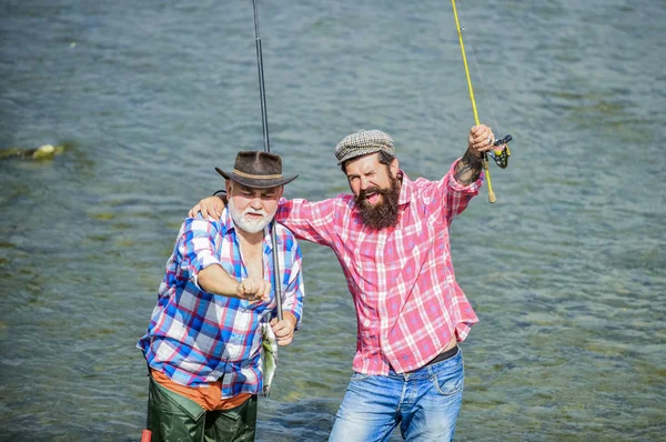 Чоловіча дружба. Батько і син рибалять. Літні вихідні. Риболовля разом. Чоловіки стоять у воді. Гарна концепція ловлі. Команда риболовлі. Щасливий рибалка з вудкою і сіткою. Хобі та спортивна діяльність — стокове фото