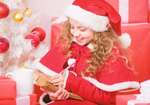 Cree en el milagro. Carta para Santa. Lista de deseos. Disfraz de niño santa disfrutar de la víspera de Navidad. Niña niña sostener pluma y papel cerca del árbol de Navidad carta de escritura. Niño escribir carta a santa claus —  Fotos de Stock