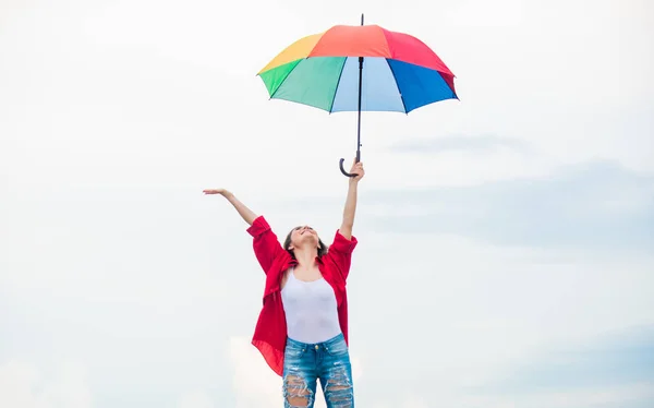 Welcoming fall. Pretty woman with colorful umbrella. Rainbow umbrella. Rainy weather. Good mood. Good vibes. Open minded person. Girl feeling good sky background. Easy and free. Good weather