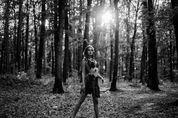 Enjoying her beauty. ethnic tribal fashion. deep forest. sexy girl in leather suede clothes. cougar female. amazon woman. sexy witch. wild woman in forest. female silhouette through the sun rays.