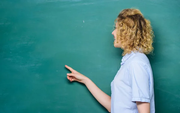 woman teacher at school lesson. back to school. woman likes studying. knowledge day. empty blackboard information. student pointing at blackboard. university or college. copy space. Modern school