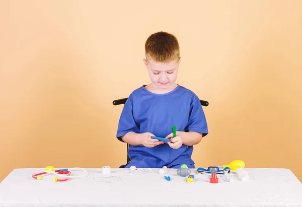 Medical examination. Medical education. Play game. Boy cute child future doctor career. Healthy life. Kid little doctor sit table with stethoscope and medical tools. Medicine concept. Health care