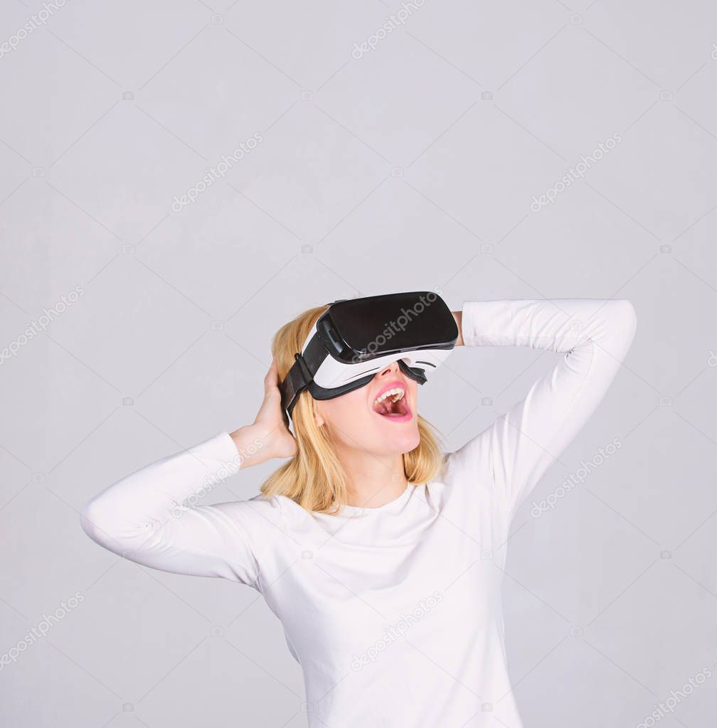 Amazed young woman touching the air during the VR experience. Portrait of young woman wearing VR goggles, experiencing virtual reality using 3d headset. Funny young woman with VR.