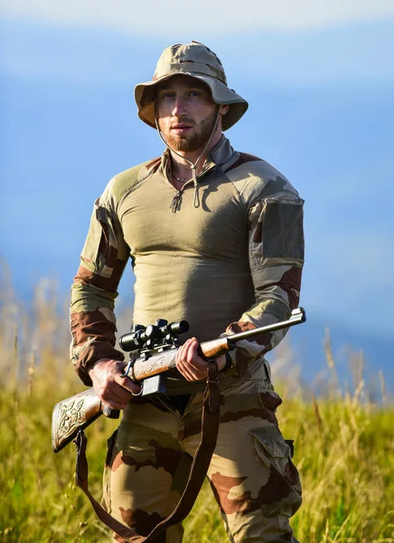 Hunter segura na espingarda. Hunter montanhas paisagem fundo. Foco e concentração caçador experiente. Pronto para disparar. Forças do exército. Roupas militares de homem com arma. Guerreiro brutal. Espingarda para caça — Fotografia de Stock