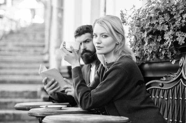 Morning coffee. Couple in love on romantic date. First meet of girl and mature man. Brutal hipster and girl drink coffee. woman and man with beard relax in cafe. reading and drinking coffee in care