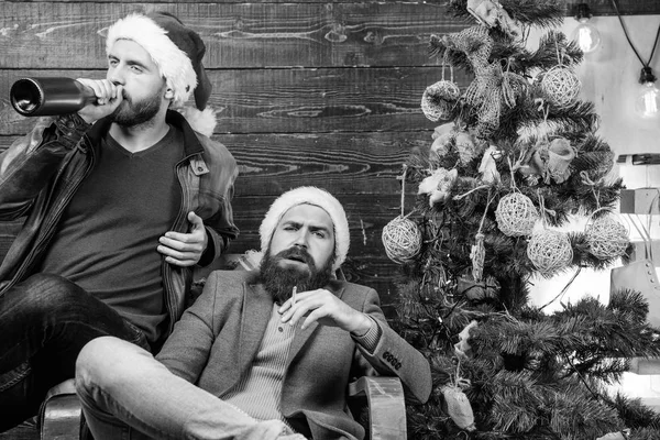 Brutální muži oslavit nový rok u vánočního stromu. Špatné návyky kopnout do konce roku. Zbavte se škodlivých návyků. Jak prolomit špatné návyky. Muži pijí šampaňské a kouření. Nové usnesení let — Stock fotografie