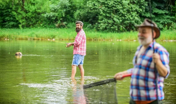 Vousatý muž chytá ryby. Dospělý muž s kamarádem. Rybář s rybářským tyčinkou. Letní prázdniny. Život je vždycky lepší, když rybajím. Aktivita a hobby. Rybníček říční jezera — Stock fotografie