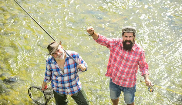 Sommerfreizeit. Fischer Angelausrüstung. Hobby-Sport. Fischerfreunde stehen im Fluss. Fische, die normalerweise in freier Wildbahn gefangen werden. Männer bärtige Fischer. Wochenenden zum Angeln. Aktiver sonniger Tag — Stockfoto