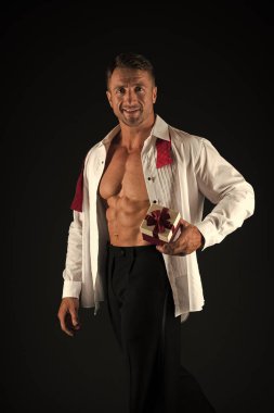 Onun için mükemmel bir romantik hediye. Yakışıklı adam siyah arka planda hediye tutuyor. Fit gövdeli ve hediye kutusu olan atletik adam. Seksi maço kas altı paketi abs ve doğum günü veya sevgililer hediye gösteren