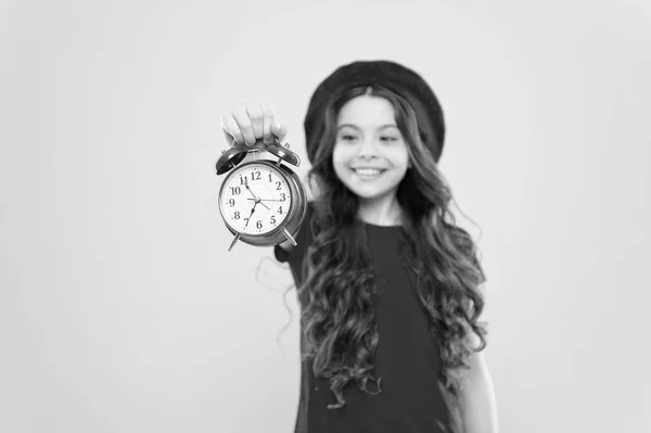 Niño parisino en amarillo. peluquero belleza. niño con despertador. Moda atemporal. chica feliz con el pelo rizado largo en boina. Niña en sombrero de estilo francés. gestión del tiempo. tiempo para diseñar — Foto de Stock