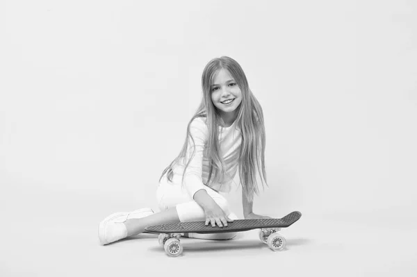 Menina se divertindo com penny board fundo rosa. Criança adorável criança cabelo longo adoram passeio penny board. Feliz infância. Montar penny board e fazer truques. A rapariga gosta de andar de skate. Estilo de vida ativo — Fotografia de Stock