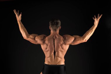 Egzersiz yoluyla kas kütlesini artırmak. Siyah arka plan üzerinde Kas adam geri görünümü. Güçlü sporcu triceps ve pazı kasları ile silah yükselterek. Fit vücut geliştirmeci kas gücü gösteren