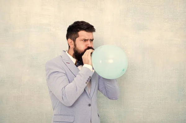 Man inflating a blue balloon. Bearded man with balloon. Happy birthday. preparation to party, celebration. Praparation to birthday party. Birthday party balloon. Party balloon. stylish event manager
