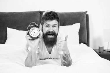 Evde boş zamanlarımın tadını çıkarıyorum. çalar saat ile mutlu sakallı adam hipster. yatak odasında acımasız uykulu adam. yatakta pijama sakallı erkek. uykuda ve uyanık. enerji ve yorgunluk. zaman yönetimi