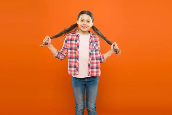 Sinto-me brincalhão. Cabelo comprido. menina pequena camisa xadrez. criança feliz. feliz dia das crianças. felicidade infantil. menina laranja fundo. moda infantil. Menina da escola sorridente. uniforme de trabalhador — Fotografia de Stock