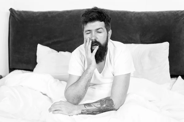 Sovraccarico. brutale uomo assonnato in camera da letto. L'hipster barbuto dorme la mattina. addormentato e sveglio. maschio maturo con barba in pigiama sul letto. energia e stanchezza. uomo stanco sentirsi oberato di lavoro — Foto Stock