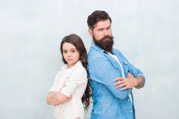 Daughter needs his unconditional love. Small daughter child and bearded man with serious look. Cute little daughter and father keeping arms crossed on grey background. Treating his daughter with love