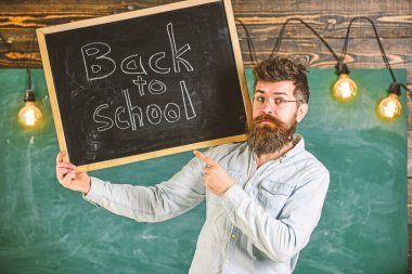 Gözlüklü öğretmen okula geri başlık ile tahta tutar. Lise konsepti. Sakallı ve bıyıklı adam sıkı bir yüz üzerinde öğrencileri karşılıyor, backgroun üzerinde tebeşir