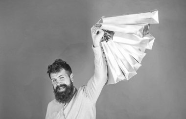 Satış sezon indirimlerle alışveriş adam. Sakal ve bıyık tutan alışveriş torbaları, kırmızı arka planı olan adam. Mutlu yüz hipster bağımlısı alışveriş veya Alışverişkoliğin. Alışveriş kavramı