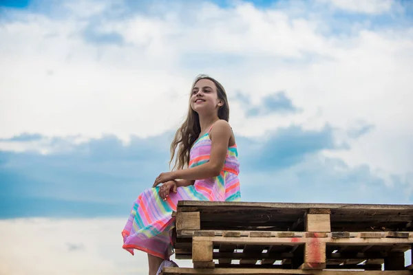 Kind gelukkig klein meisje. Gratis en zorgeloos. Onschuld concept. Gelukkige internationale Kinder dag. Gelukkige kindertijd. Schattige kleine meisje zomer jurk buiten hemel achtergrond. Fijne vakantie. Genieten van ontspanning — Stockfoto