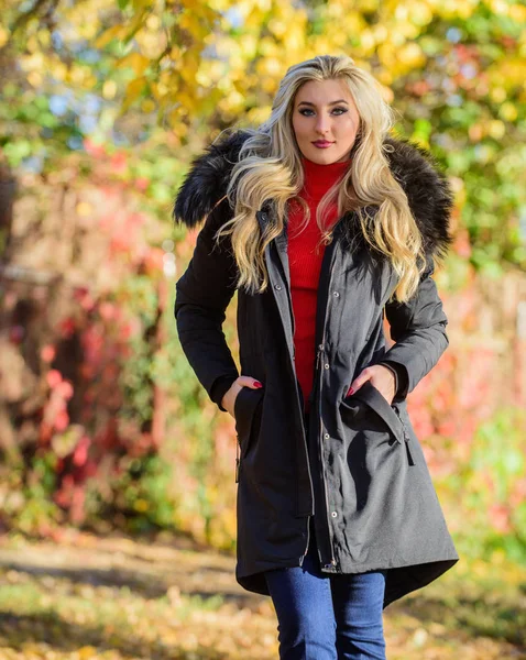 Create fall outfit to feel comfortable and pretty. Woman long blonde hair wear stylish outfit with parka. Modern outfit for youth. Girl in warm coat stand in park nature background defocused — Stockfoto