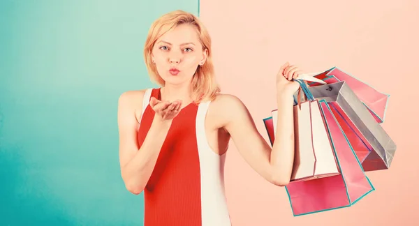 Consejos para comprar ventas con éxito. Chica disfrutar de las compras o acaba de recibir regalos de cumpleaños. Mujer vestido rojo sostienen manojo bolsas de compras fondo rosa azul. Compra todo lo que quieras. Chica satisfecha con las compras —  Fotos de Stock