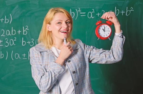 ¿Qué hora es? La profesora sostiene el despertador. Profesora formal de la escuela de moda. Es hora de estudiar. Bienvenido año escolar maestro. Educador experimentado comenzar la lección. Ella se preocupa por la disciplina — Foto de Stock