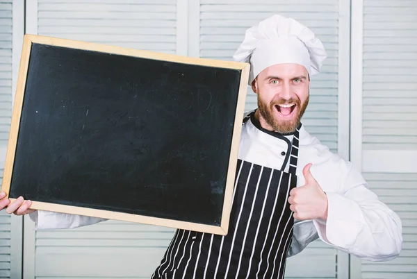 Daumen hoch für unsere Cateringschule. Meisterkoch gibt Kochkurs. Chefkoch unterrichtet Meisterklasse in Kochschule. Ausbildung zum Kochen und zur Zubereitung von Lebensmitteln. Mann hält Tafel, kopiert Raum — Stockfoto