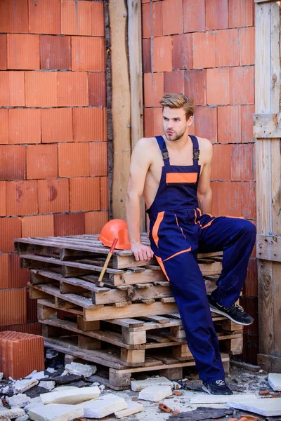 Confident worker. professional repairman hard hat fittings. man builder in work clothes. building and construction. engineer with tool. architect repair and fix. worker relax wooden pallet — Stock Photo, Image