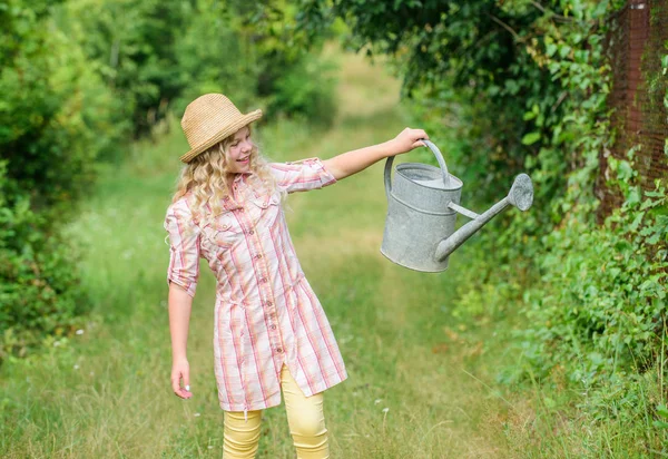 Enjoying her work. environment ecology. nature protection. little girl farmer care plants. farming and agriculture. spring country side village. summer season. small girl with watering can. earth day